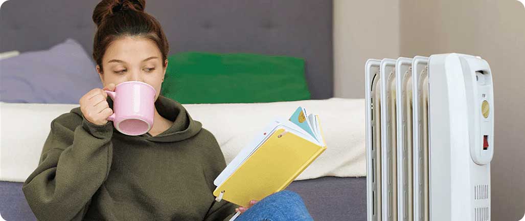Woman on floor warming up by portable radiator